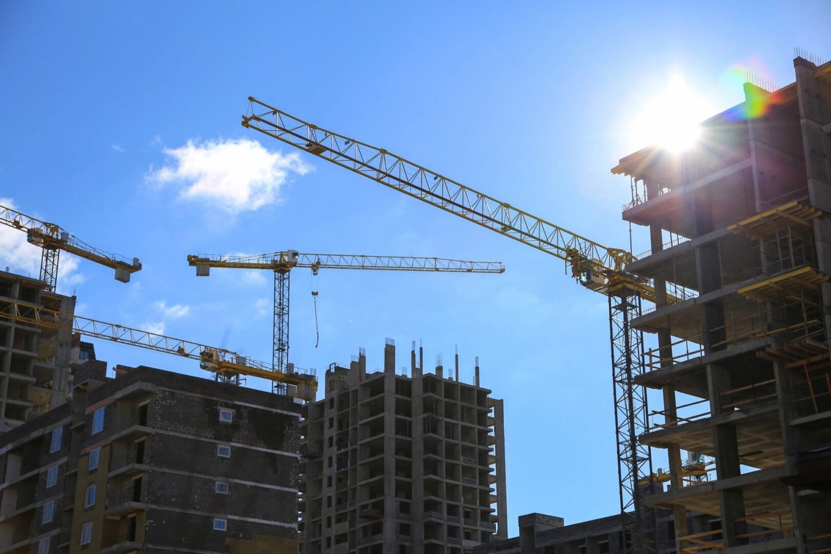 Construction cranes in front of a building under construction.