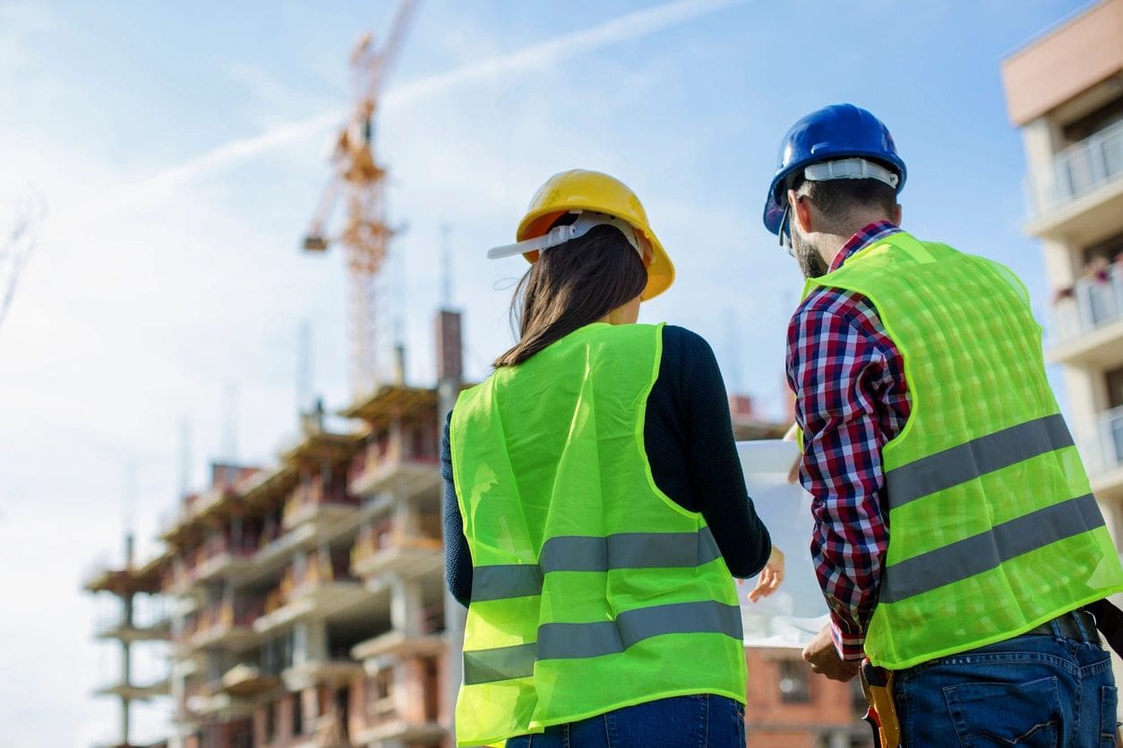 Two construction workers standing in front of a construction site.