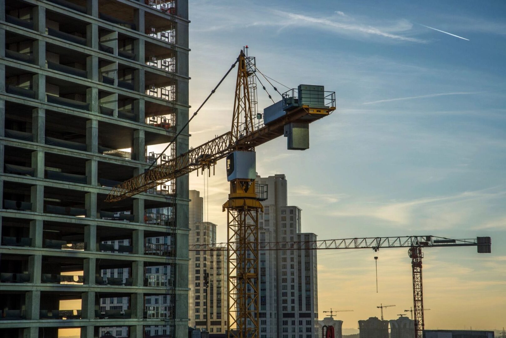 A crane is on a construction site in front of a skyscraper.