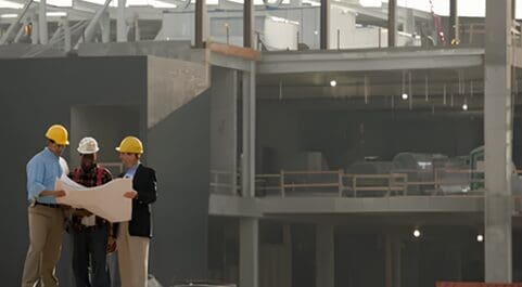 three man in yellow hard hat holding a sign.