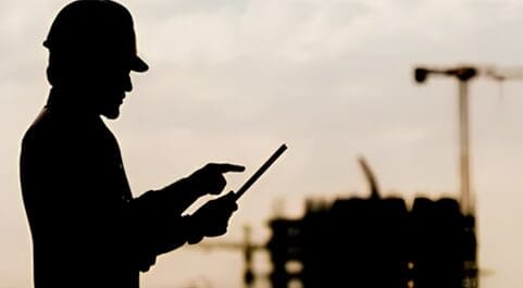 A man on a hard hat holding a tablet